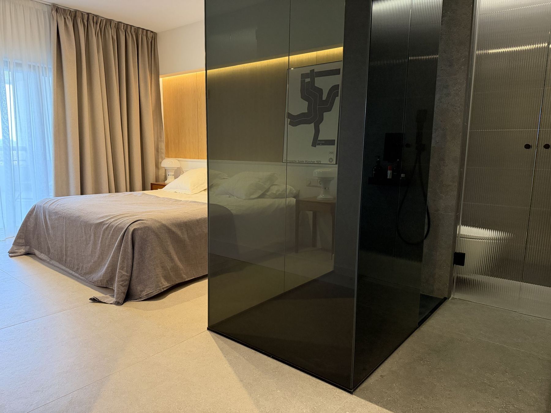 Dormitorio y baño separados por un volumen de vidrio ahumado